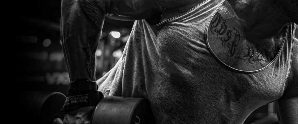 Muscular athlete lifting a heavy dumbbell in a gym, black and white — Octagon Labs research-grade peptides for athletic performance